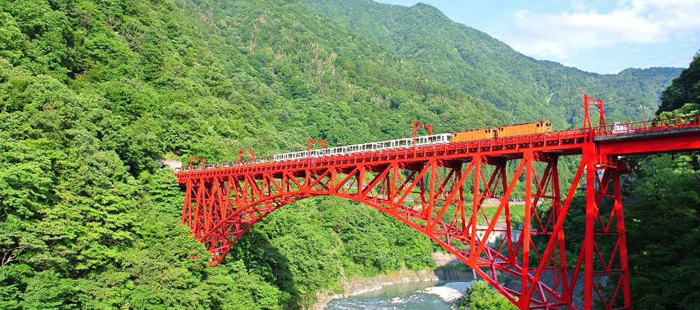 新緑の黒部峡谷を走るトロッコ電車